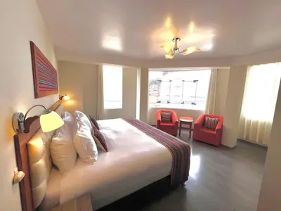 a hotel room with a bed and a table and chairs at Hotel Chinchero Boutique & Tours in Chinchero