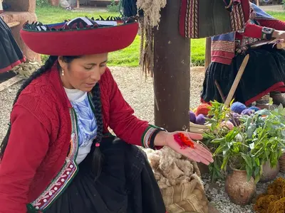 a woman wearing a hat holding a red flower at Hotel Chinchero Boutique & Tours in Chinchero