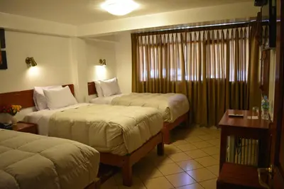 a hotel room with two beds and a table at Casa De Luz Hotel in Machu Picchu