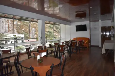 a dining room with tables and chairs and windows at Casa De Luz Hotel in Machu Picchu