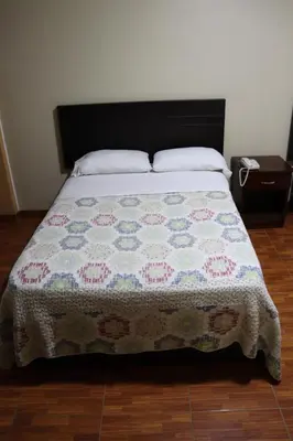 a bed with a quilt on it in a bedroom at Gran Hotel Virrey in San Ramón