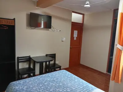 a bedroom with a bed and a table and a tv on the wall at Gran Hotel Virrey in San Ramón