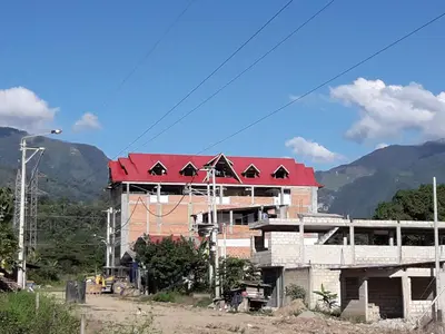 a building with a red roof with mountains in the background at Gran Hotel Virrey in San Ramón