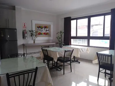 a kitchen with two tables and chairs in a room at Gran Caral Hotel in Barranca