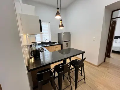 a kitchen with a counter and chairs in a room at Sori Apartments in Lima