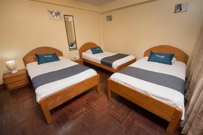 a room with two beds and a mirror at Ayenda Posada Inn in Cusco