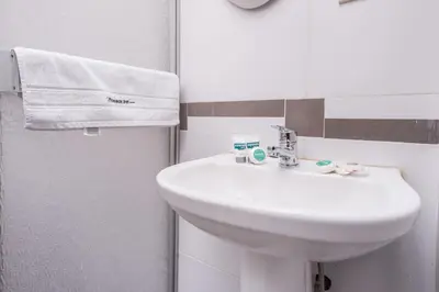 a white bathroom with a sink and a towel at Ayenda Posada Inn in Cusco