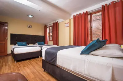 three beds in a room with red curtains at Ayenda Posada Inn in Cusco