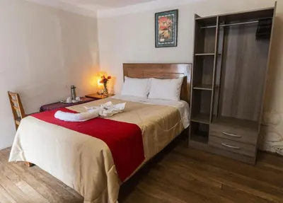 a bedroom with a large bed with a red blanket at Askha Cusco in Cusco