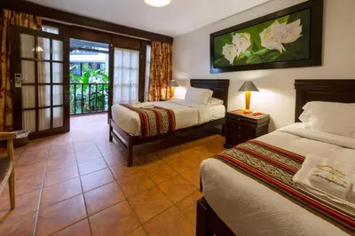 a hotel room with two beds and a balcony at Gringo Bill's Boutique Hotel in Machu Picchu