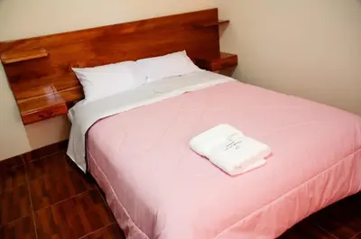 a bedroom with a large bed with a wooden headboard at La Posada D'Benjamín in Oxapampa