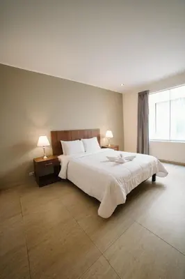 a bedroom with a large white bed with two lamps at Villa Oasis in Ica
