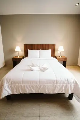 a bedroom with a white bed with two lamps at Villa Oasis in Ica