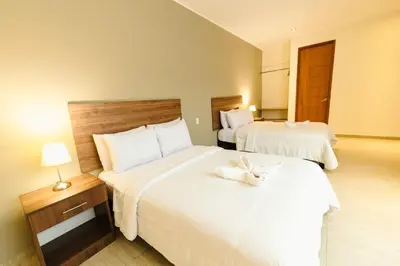 a hotel room with two beds with white sheets at Villa Oasis in Ica