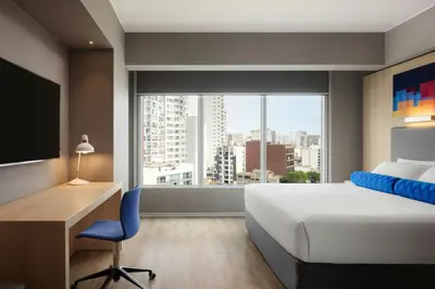 a bedroom with a bed and a desk and a large window at Aloft Lima Miraflores in Lima