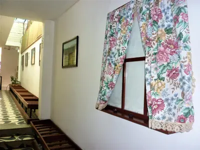a window with a floral curtain on a wall at Anccalla Inn Guesthouse in Nazca