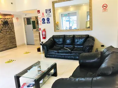 a living room with a black leather couch and a mirror at Hostal Carlos Tenaud in Lima