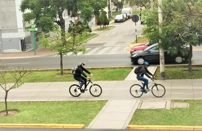 two people riding bikes down a sidewalk at Hostal Carlos Tenaud in Lima