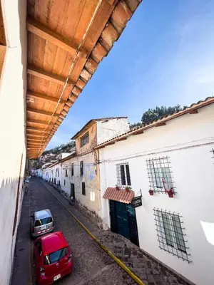 a red car parked on a street with buildings at Hotel Cusco Plaza Saphi in Cusco