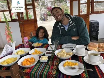 a man and a girl sitting at a table with food at Eco Hacienda Roman in Machu Picchu