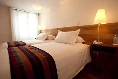 a hotel room with two beds and a telephone at Hotel Plaza de Armas Cusco in Cusco