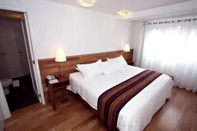 a bedroom with a large white bed and a window at Hotel Plaza de Armas Cusco in Cusco