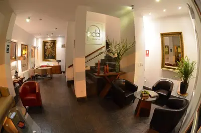a living room with a couch and chairs and a staircase at Hotel Plaza de Armas Cusco in Cusco