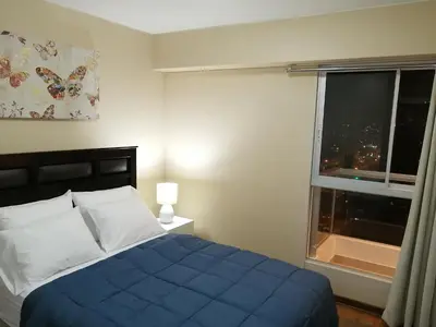 a bedroom with a blue bed and a window at Departamento BH South in Lima