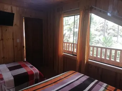 a bedroom with a bed and a window with a balcony at HOSPEDAJE CAMPOS ELÌSEOS in Oxapampa