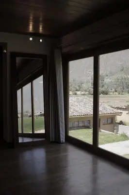 an empty room with large windows with a view of a house at Casafranca in Ollantaytambo