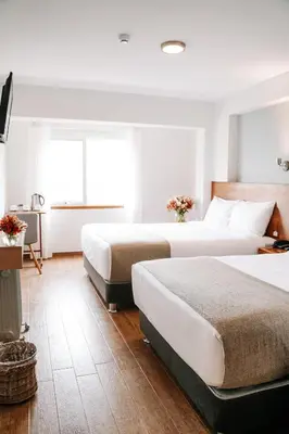 a hotel room with two beds and a television at Muru Homely Hotel Cusco in Cusco