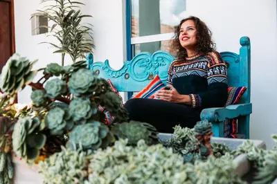 a woman sitting in a blue chair next to a bunch of cactus at Tariq Boutique in Cusco