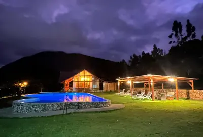 a house with a pool in the yard at night at HASSINGER RANCH Cabañas in Oxapampa