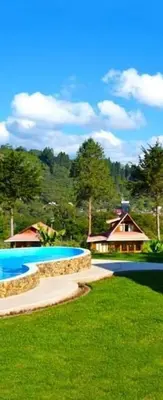 a yard with a house in the background and a house with trees at HASSINGER RANCH Cabañas in Oxapampa