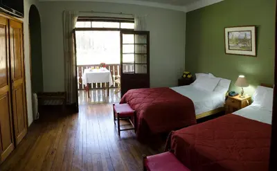 a bedroom with two beds and a table and a window at Centro Vacacional Huaychulo in Concepción