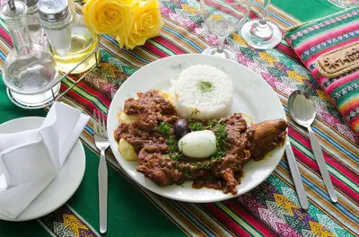 a plate of food with meat and rice on a table at Centro Vacacional Huaychulo in Concepción