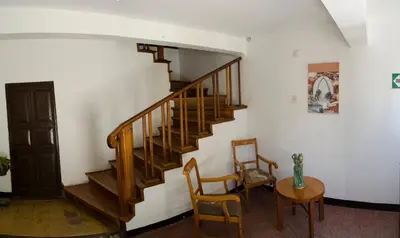 a staircase in a room with two chairs and a table at Centro Vacacional Huaychulo in Concepción