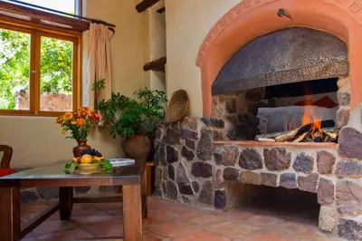 a stone fireplace in a living room with a table at Sacred Dreams Lodge in Urubamba