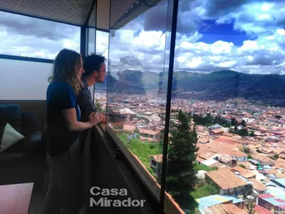 a man and woman standing in front of a window at Casa Mirador guesthouse in Cusco