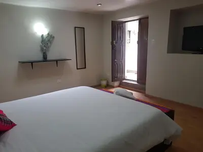 a bedroom with a large white bed and a television at Xplora Hostel Cusco in Cusco