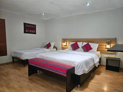 a bedroom with two beds and a bench in it at Xplora Hostel Cusco in Cusco