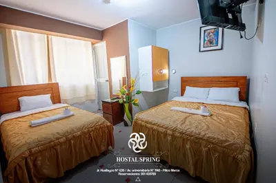a hotel room with two beds and a television at Hostal Spring II in Huánuco