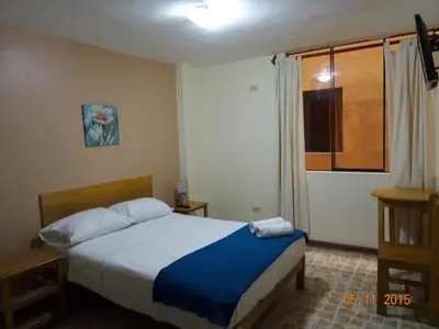 a bedroom with a bed with blue sheets and a window at Hospedaje La Videna in Lima