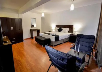 a bedroom with a bed and a desk and chairs at Ankawa Hotel Boutique in Cusco