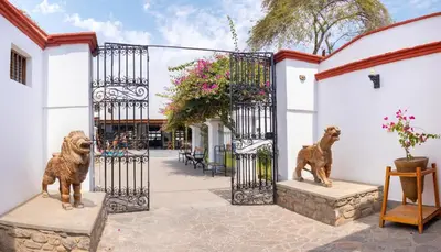 a gate with two statues of dogs in a courtyard at Bodega el Huarango in Ica