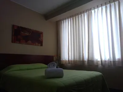 a bedroom with a green bed and a window at Hotel Sumaq Inn Sac in Lima