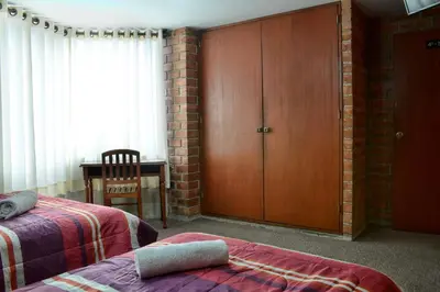 a bedroom with two beds and a wooden cabinet at Hotel Esperanza in Lima