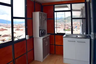 a kitchen with a refrigerator and two windows at The Chusay Rooftop in Cusco