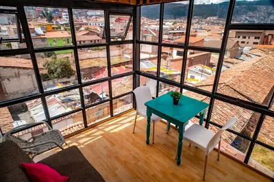 a room with a table and chairs in front of a large window at The Chusay Rooftop in Cusco