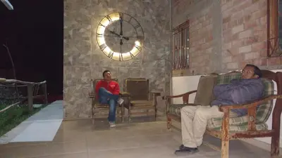 two people sitting in chairs in a room with a clock at Alojamientos Támpur in San Mateo